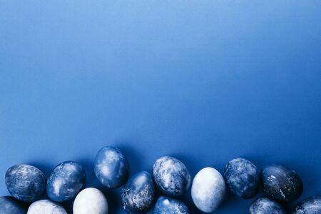 Beautiful group ombre blue Easter eggs with quail eggs and feathers on a blue background. Easter...