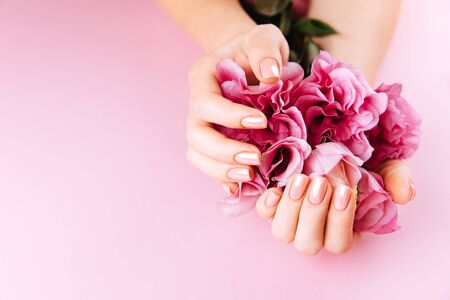 Beautiful Woman Hands with fresh eustoma. Spa and Manicure concept. Female hands with pink manicure. Soft skin, skincare concept. Beauty nails. Over beige backgroundの写真素材