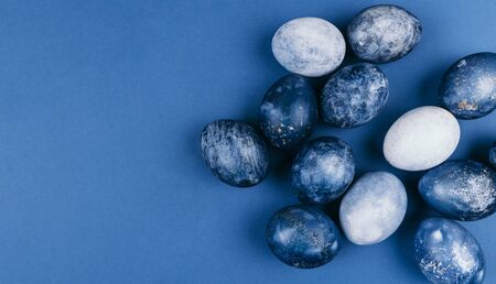 Beautiful group ombre blue Easter eggs with quail eggs and feathers on a blue background. Easter concept. Border eggs. Copy space for textの写真素材