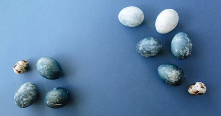 Beautiful group ombre blue Easter eggs with quail eggs and feathers on a blue background. Easter concept. Border eggs. Copy space for textの写真素材