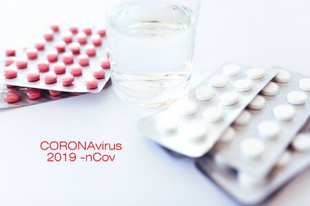 Assorted pharmaceutical medicine pills, tablets and capsules over white background. Pills on the table with a glass of water. medical topics. virus and coronovirus. top view, place for text.の写真素材