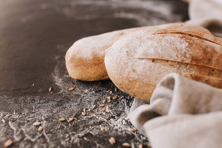 Various crispy bread and buns on the stone table, Loaf of fresh baked artisan sliced rye bread over dark texture background. Top view, copy space.の写真素材