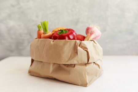 Paper grocery bag with fruits and vegetables over white background, eco shopping, zero waste, vegetarian concept.の写真素材