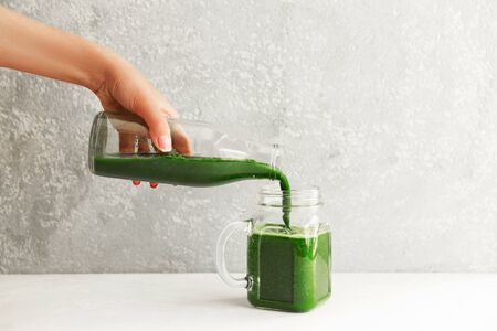 Hands pouring healthy green smoothie in a jar. Clean eating concept.の写真素材