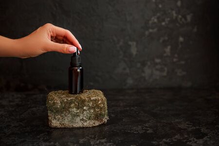Composition with women hand and brown glass bottles over Natural background of real moss on light stone surface with copy space for mockup of body care organic cosmetics.の写真素材