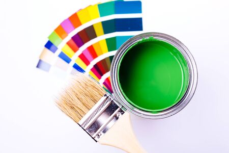 Paint brush laying on a heap of color samples. open can of green paintの写真素材