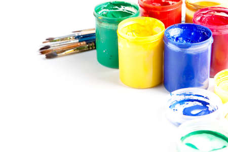 Jars of brightly coloured gouache paint with artists brushes and copyspace on a white backgroundの写真素材