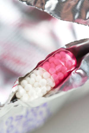 Closeup of a transparent pink and white medical capsule in silver blister packaging