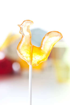 Glowing festive sugar cockerel on a stick to be used as a decoration or eaten as a lollipop as a special treatの写真素材