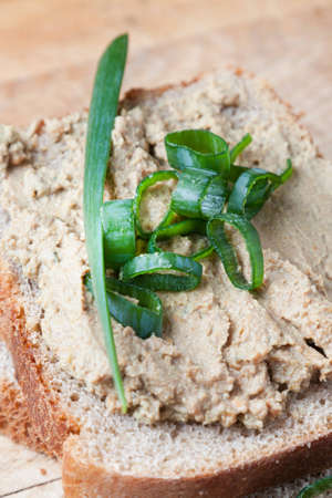 Closeup view of a serving of liver pate spread on sliced brown bread and garnished with herbsの写真素材