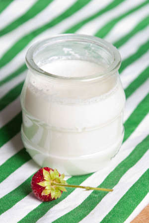 Fresh natural healthy low fat yoghurt in a glass pot on a wooden table ready to be served for breakfastの写真素材