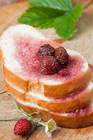 Stack of fresh bread slices topped with strawberry jam containing whole fruit dribbling down onto the slices belowの写真素材