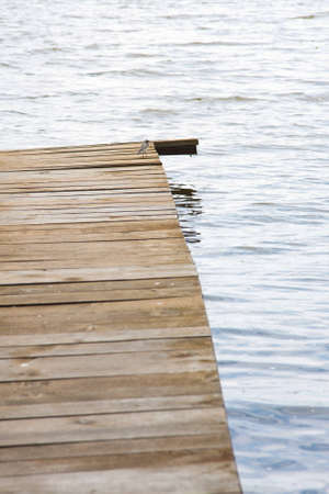 Background of a rustic wooden jetty jutting into a lake with two little waterbirds perched on the...
