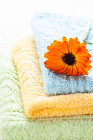Colorful towels and orange flower on top of them - spa conceptの写真素材