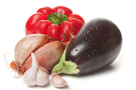 Fresh whole eggplant, garlic, onion and red bell pepper shining with moisture droplets on the skin after being washed before being used as cooking ingredientsの写真素材