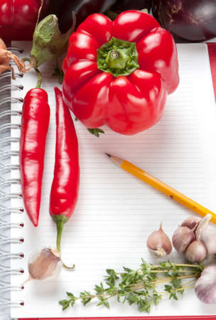 Blank lined notepad with a pencil and fresh ingredients including thyme, garlic and chili peppers for your recipe or cooking tipsの写真素材