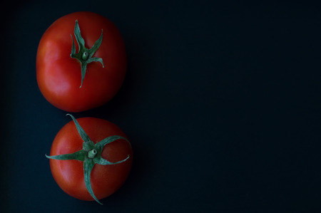 Two tomatoes on black backgroundの写真素材