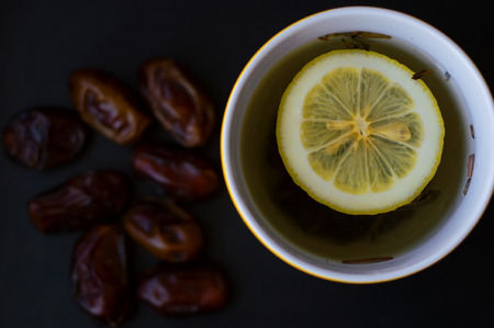 Tea, lemon and dates on a black backgroundの写真素材