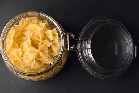 Farfalle stored in a glass jar, natural light, black backgroundの写真素材