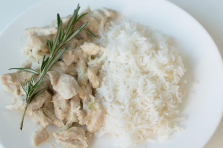 Portion of white rice and chicken slices cooked in cream and decorated with fresh rosemary leaves. Healthy cooking. Diet eating conceptの写真素材