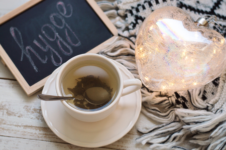 Green tea in white cup, heart shaped lantern, knitted blanket and blackboard with wordの写真素材