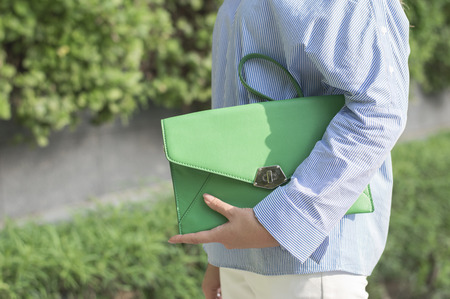 Teenage girl sitting on the wooden bench in the park. Young female with brown hair in warm grey cardigan and black jeans. Autumn moodの写真素材