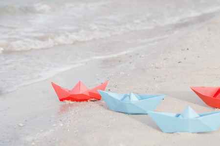 Red and blue paper ships on the beach. Paper toy boatsの写真素材