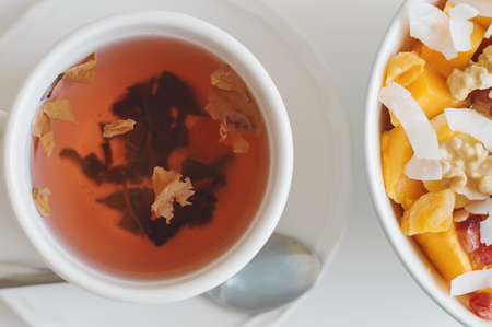 Green tea with hibiscus and rose petals served with a bowl with fresh fruit salad. Healthy vegan breakfastの写真素材