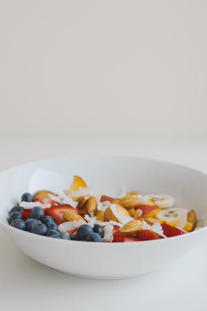 Vertical photo of healthy breakfast with oats, blueberry, peach, strawberry, almond, banana and...