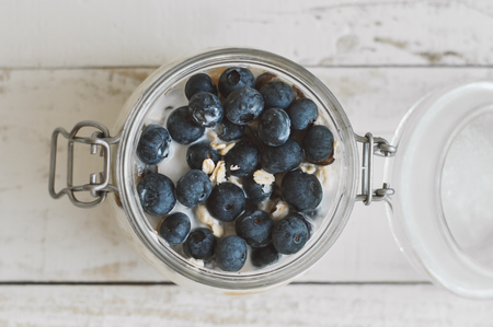 Jar with overnight oats with fresh blueberry. Healthy yougurt with coconut milk and fruits, top viewの写真素材