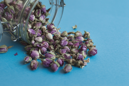 Herbal tea in a glass jar. Dried rose buds on blue backgroundの写真素材