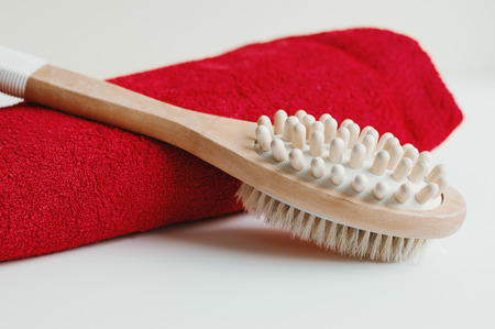 Wooden brush for dry body massage and red cotton towel on white background. Cellulite treatment. Self massage toolの写真素材