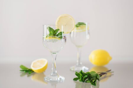 Two glasses of mineral water with lemon and fresh mint on glass surface. Sparkling drink with citrus and herbsの写真素材