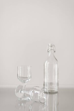 Two empty wine glasses and bottle for water on transparent tableの写真素材