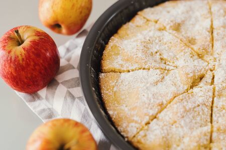 Sliced homemade apple pie with icing sugar served on a napkin with fresh whole applesの写真素材