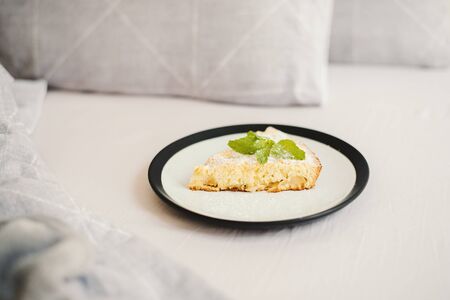 Breakfast in bed: homemade apple pie with powdered sugar and fresh mint on a plateの写真素材