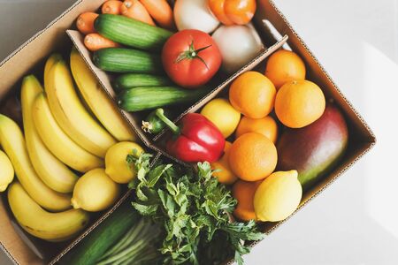 Paper box with fresh fruits and vegetables. Food delivery service. Grocery shoppingの写真素材