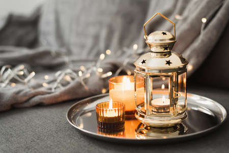 Golden lantern and burning candles on a metal tray. Traditional decor for muslim holidays. Eid Al...