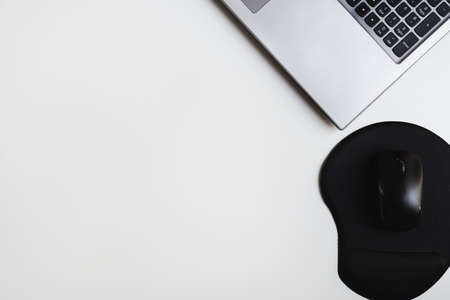 Laptop keyboard and computer mouse with ergonomic mouse pad for comfortable wrist position while working. Clean office desk flat layの写真素材