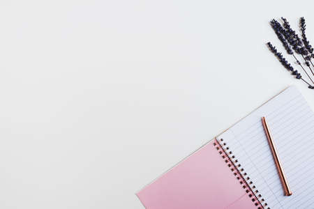Pink notebook with clean pages, metal pen and dried lavender flower on white background. Feminine flatlayの写真素材