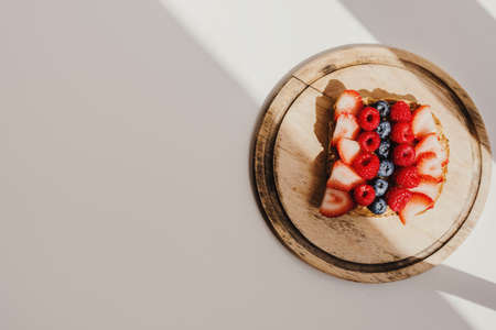 One peanut butter toast with whole grain bread and fresh seasonal berries on wooden board. Sweet breakfast toastの写真素材