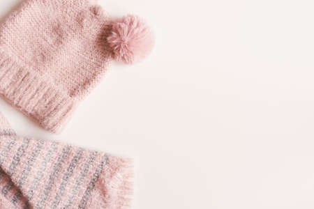 Handmade knitted hat and scarf of pink color on white background, top view, copy space. Warm...