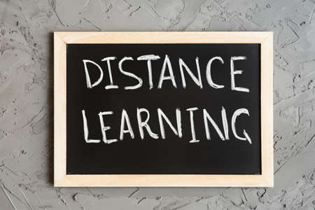 Phrase "Distance Learning" written on a blackboard, concrete wall as background. Online education conceptの写真素材
