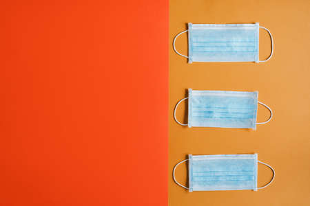 Medical face masks on paper background of orange color, flat lay, space for text. Fall season 2020の写真素材