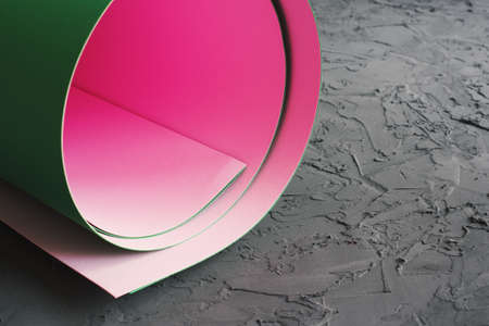 Paper roll of pink and green color on textured concrete background