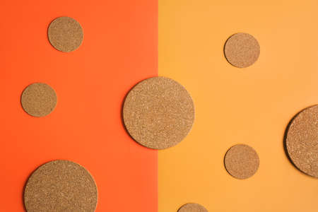 Cork coasters of different sizes on background of orange and yellow color, top view