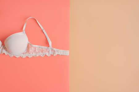 Bra of beige color on pastel pink and beige background, space for text. Breast cancer awareness month concept