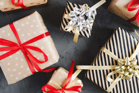 Gift boxes wrapped in craft paper with red and yellow ribbons on concrete background, top view....