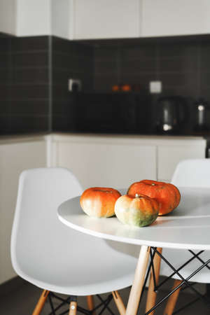 Three pumpkins on a white dining table in the kitchen area. Traditional autumn food ingredient. Fall...