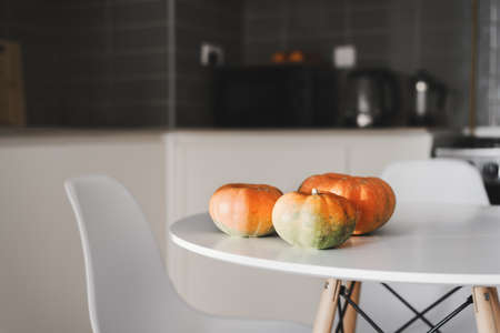 Small pumpkins on a white dining table standing in the kitchen area. Fall season symbolの写真素材